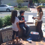 A woman is handing out money to two kids.